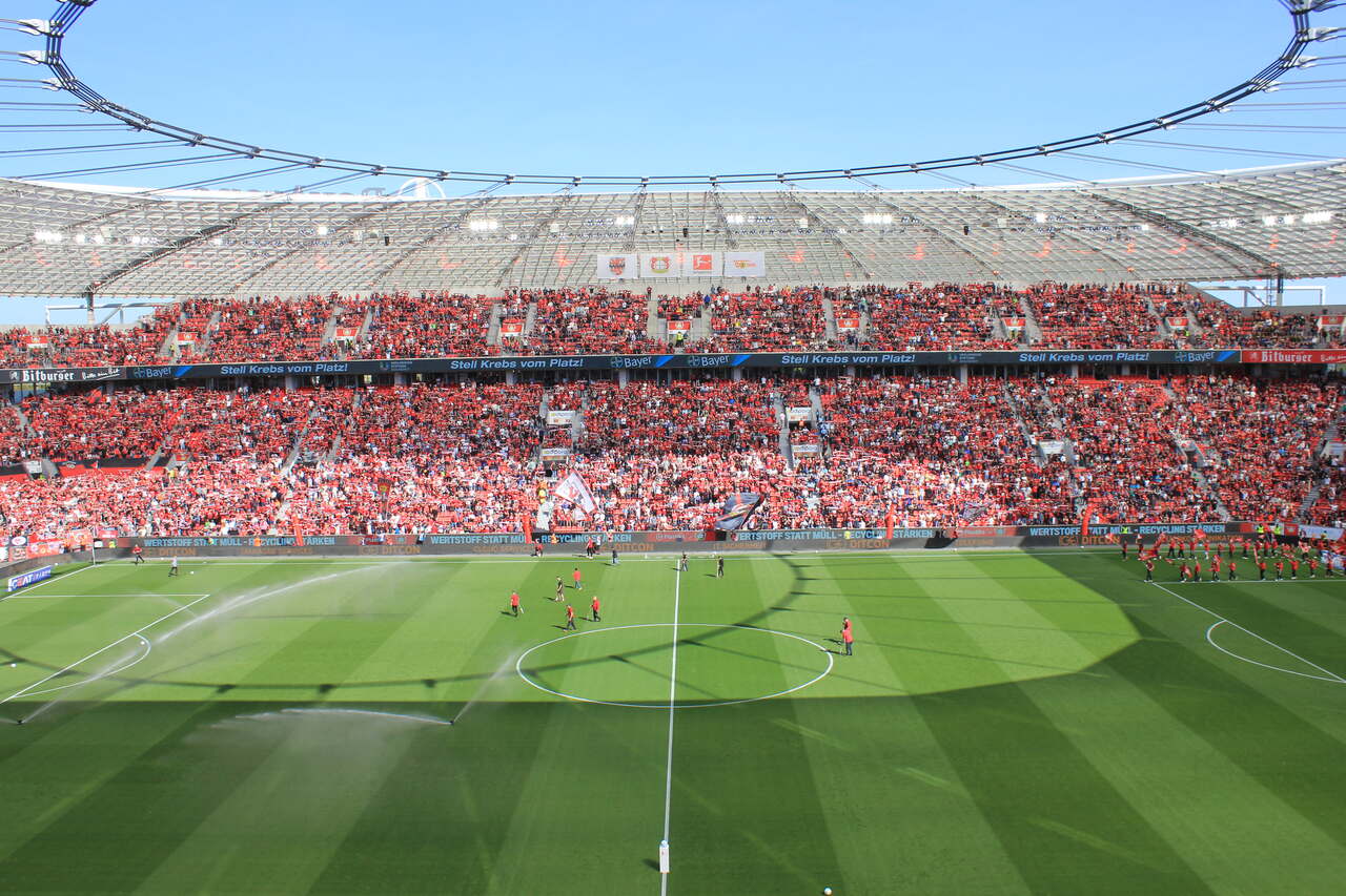 Estadio de fútbol repleto de aficionados durante un partido en el BayArena, sede del Bayer 04 Leverkusen, que colabora con Plastiks en iniciativas de recuperación de plástico.