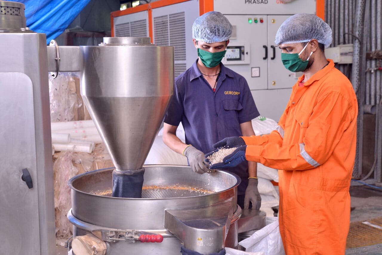 two poeple in plastic recycling company in a formal uniform and masks working - Gemcorp's workers