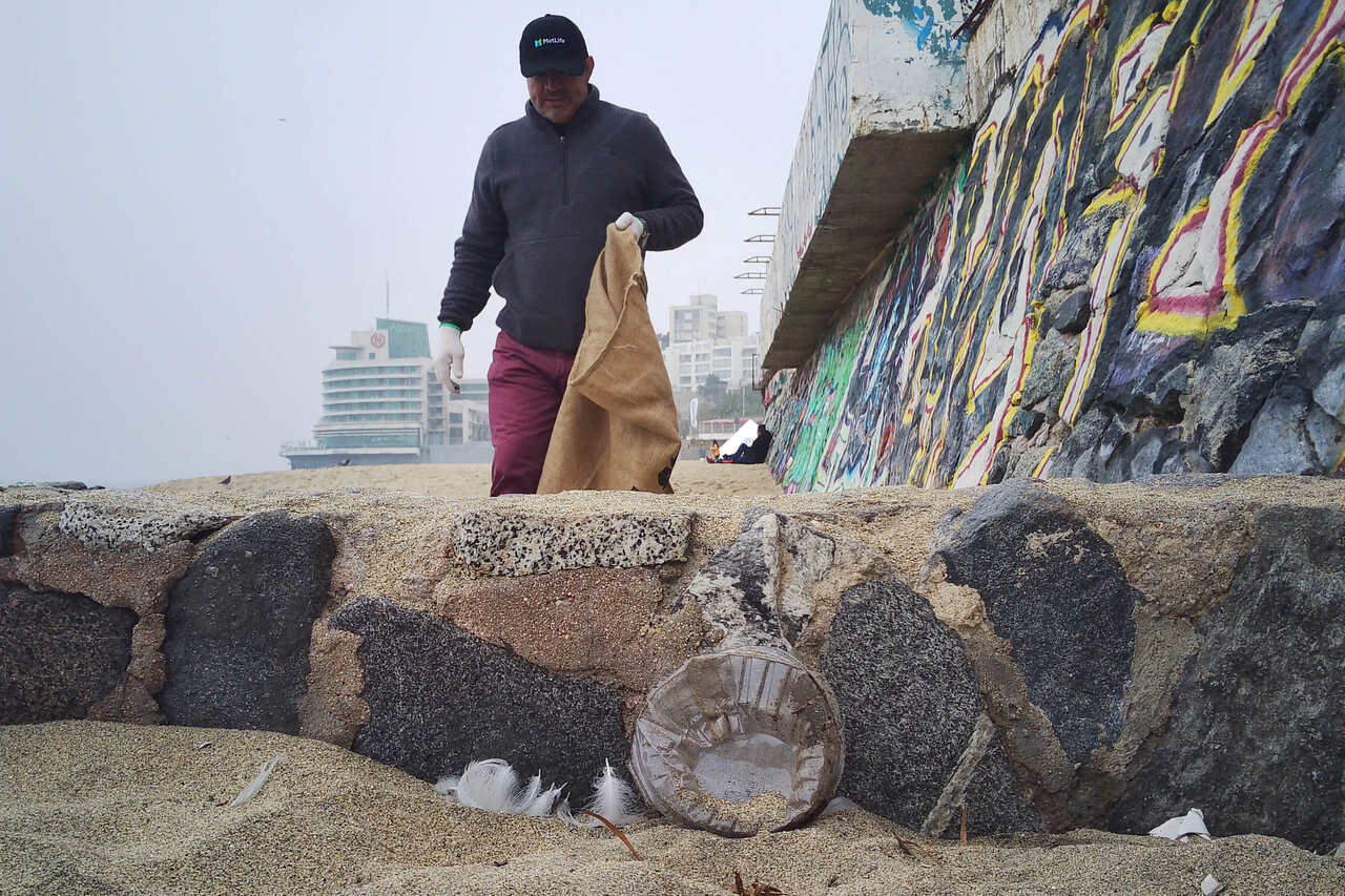 a man picking up plastics waste from the beach