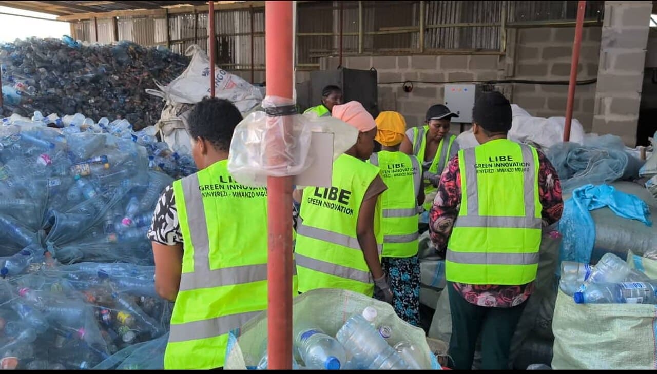 A team of workers at Libe Green Innovation in Tanzania process and sort collected plastic waste. Wearing high-visibility vests, they contribute to verified plastic recovery efforts, ensuring sustainable waste management.